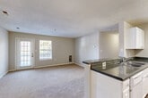 Located at 13671 Cridercrest Pl in Woodbridge, VA, this well-appointed 2-bedroom, 2-bathroom residence offers a thoughtfully designed single-story layout. The open-concept living and dining area is bright and welcoming, featuring plush wall-to-wall carpeting, neutral tones, and large windows and a glass patio door that fill the space with natural light and provide access to a private outdoor patio. The kitchen is equipped with white cabinetry, dark laminate countertops, a full suite of white appliances including a range and refrigerator, and durable wood-look flooring — all accented by a pendant light above the prep area. A convenient peninsula counter opens the kitchen toward the dining area, ideal for everyday functionality. The primary bedroom offers a comfortable footprint with a double-door closet and natural light from a window with blinds. The second bedroom is similarly carpeted and well-lit. Both bathrooms feature white vanity cabinetry, granite-style countertops, and large mirrors. A dedicated in-unit laundry area with a full-size washer and dryer adds everyday convenience. Multiple closets throughout provide ample storage, completing this practical and comfortable Woodbridge home.