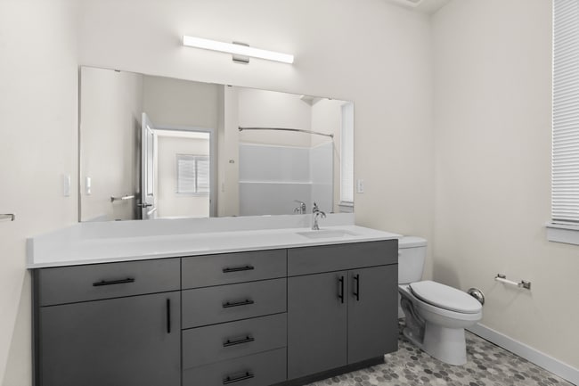 Comience el día en un baño elegante con acabados modernos, amplio espacio de almacenamiento y una espaciosa zona de tocador. - 27 West Apartments