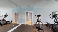 Located at 1100 Deer Harbor Dr in Garner, NC, this single-floor fitness facility is thoughtfully designed to support a comprehensive workout experience. The space is painted in a calming light blue palette throughout, with durable rubber flooring across the exercise areas providing both safety and functionality.

The main gym area is expansive and well-lit, accommodating an impressive array of cardio equipment including elliptical trainers, stationary bikes, treadmills, and rowing machines. Ceiling fans are strategically placed overhead to maintain comfortable airflow during workouts, and natural light filters in through multiple windows. Large wall-mounted mirrors in select zones enhance the sense of space and allow for form monitoring during exercise.

A dedicated strength training section houses multi-function cable machines, weight benches, and resistance equipment, alongside a wall-mounted flat-screen television for entertainment. A collection of medicine and stability balls rounds out the functional fitness offerings.

Separate from the main gym, a quiet business center features a built-in granite countertop desk spanning two walls, tile flooring, and dual workstations with computers — ideal for residents needing a professional workspace. Natural light enters through two windows, and a ceiling fan keeps the room comfortable. The overall facility is clean, organized, and designed to serve a variety of fitness and productivity needs.