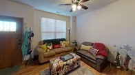This two-floor residence offers a well-designed layout with functional living spaces throughout. The kitchen is a standout feature, equipped with stainless steel appliances including an electric range and over-the-range microwave, rich dark wood cabinetry, and granite countertops. A breakfast bar peninsula provides additional prep space and casual seating, while light hardwood flooring ties the kitchen seamlessly into the adjoining living area. The living room is bright and comfortable, featuring a ceiling fan with light fixture, a large window with blinds that allows natural light to filter in, and warm hardwood floors underfoot. Multiple bedrooms are spread across both floors, each carpeted for comfort and outfitted with ceiling fans. The bedrooms feature windows with blinds or sheer curtains and offer practical layouts suitable for rest and study. The space includes several bathrooms, each featuring dark wood vanities with light countertops, a large mirror, and tile flooring. Bathrooms are equipped with either a shower-tub combination or standalone shower. Throughout the residence, a consistent design palette of neutral wall tones, dark wood accents, and warm flooring materials creates a cohesive and inviting atmosphere across all levels.