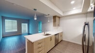 Located at 21425 Vanowen St in the Canoga Park neighborhood of Los Angeles, this modern single-story unit offers a thoughtfully designed layout with contemporary finishes throughout. The open-concept kitchen serves as a central feature, showcasing light wood cabinetry with sleek bar-pull hardware, crisp white quartz countertops, and a classic subway tile backsplash. A peninsula with pendant lighting extends the workspace and creates a natural division between the kitchen and living area. Stainless steel appliances, including an electric range, over-the-range microwave, and dishwasher, complete the kitchen. The living area is finished with rich dark hardwood flooring that extends throughout the main living spaces, while bedrooms feature plush neutral carpet. Each bedroom benefits from natural light through window blinds, and one bedroom includes a closet with direct access to an en-suite bathroom. Both bathrooms are finished with light wood vanities, white quartz countertops, full-width mirrors, and tiled tub-and-shower combinations. The primary bathroom offers a double-sink vanity and a frameless sliding glass shower door, adding a refined touch. Recessed lighting and a clean, neutral color palette unify the space with a bright, contemporary ambiance throughout.