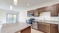 Located at 350 Bishops Way in Brookfield, Wisconsin, this thoughtfully designed one-bedroom, two-bathroom residence offers a well-appointed single-floor layout with a functional and modern aesthetic. The open-concept kitchen and living area serves as the heart of the home, featuring rich dark-brown cabinetry, stainless steel appliances, granite countertops, and a central island with pendant lighting overhead. Light hardwood-style flooring runs throughout the main living areas, contributing to a bright and cohesive atmosphere. Large windows and a glass-panel entry door allow abundant natural light to fill the space while providing views of the surrounding greenery.

The bedroom is carpeted for comfort and includes a generous window with outdoor views. An additional office provides a dedicated workspace, while four closets offer exceptional storage throughout the unit. The in-unit laundry area adds everyday convenience.

Both bathrooms are finished with dark cabinetry, granite-topped vanities, and light wood-style flooring. The primary bathroom includes a soaking tub, while the second bathroom features a clean, open layout. Neutral warm tones are used throughout, creating a calm and welcoming ambiance across every room in this well-organized Brookfield residence.