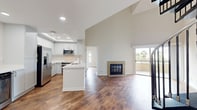 This contemporary apartment, located at 3400 Avenue of the Arts in Costa Mesa, California, offers a harmonious blend of modern design and functional living space. Spanning 1,260 square feet across two floors, the property showcases a thoughtful layout with 920 square feet on the ground floor and 340 square feet above.

The heart of the home is the sleek, U-shaped kitchen, featuring pristine white cabinetry, stainless steel appliances, and a recessed ceiling with LED lighting. The adjacent living area boasts a fireplace with a granite surround and sliding glass doors leading to a balcony, flooding the space with natural light and offering a glimpse of palm trees outside.

Storage is abundant, with a custom-designed walk-in closet featuring built-in shelving, drawers, and hanging space. The bathroom continues the modern aesthetic with a glass-enclosed shower and sleek fixtures.

Throughout the apartment, warm-toned hardwood flooring creates a cohesive look, complemented by crisp white walls and recessed lighting. The upper level, accessible via an interior staircase, provides additional living space, possibly serving as a bedroom or home office.

High ceilings and an open floor plan contribute to an airy, spacious feel, while the neutral color palette offers a blank canvas for personal style. This apartment seamlessly combines contemporary design with practical living, making it an ideal urban retreat in the heart of Costa Mesa.