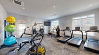 Located at 226 Bucknoll Road in Manheim, Pennsylvania, this fitness center offers a dedicated exercise space and connecting hallway across a single floor. The exercise room is finished with neutral gray walls, recessed lighting, and durable patterned carpet flooring, creating a clean and functional environment suited for a variety of workouts.

The space is comprehensively equipped for both cardio and strength training. Cardio equipment includes multiple treadmills, an elliptical, an air bike, and a stationary cycle. For strength and resistance training, the room features a multi-station cable machine, a full rack of dumbbells, adjustable workout benches, and rowing machines. Additional fitness accessories such as stability balls, medicine balls, and exercise mats are neatly organized along the walls using dedicated storage racks and holders.

Large windows with blinds allow natural light to fill the room, enhancing the open and airy atmosphere. A wall-mounted flat-screen television is positioned for easy viewing during workouts. Full-length mirrors on one wall further amplify the sense of space and allow users to monitor their form. The room is accessible via a exterior door with an emergency exit, and a frosted-glass interior door connects to the hallway. The overall design is modern and well-organized, supporting a comprehensive fitness experience.