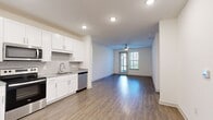 This single-story home in Jacksonville, FL offers a practical and well-designed layout across four bedrooms and two bathrooms. The open-concept kitchen and living area serves as the heart of the home, featuring wood-look hard flooring, recessed lighting, and a ceiling fan. The kitchen is outfitted with white shaker-style cabinetry, granite countertops, a subway tile backsplash, and a full suite of stainless steel appliances including a side-by-side refrigerator, electric range, built-in microwave, and dishwasher. The living area extends toward a glass exterior door flanked by windows, allowing natural light to fill the space and providing outdoor access. The bedrooms are carpeted and include built-in closets with wire shelving. Both bathrooms feature granite-topped vanities, white cabinetry, and wood-look tile flooring. A dedicated laundry room houses a full-size washer and dryer with overhead wire shelving. Two hallways connect the rooms efficiently, and a separate closet provides additional storage. The overall aesthetic is clean and contemporary throughout.