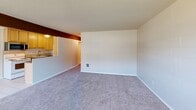 Located at 2040 Wheaton Way in Bremerton, WA, this 2-bedroom, 1-bathroom unit offers a practical and comfortable single-floor layout. The combined kitchen and living room area forms the heart of the space, with the galley-style kitchen showcasing light wood cabinetry, dark granite-style countertops, tile flooring, and a full suite of appliances including an electric range, built-in microwave, and refrigerator. A pass-through connects the kitchen to the carpeted living room, which features a textured ceiling and a wide bank of windows that fill the space with natural light and views of the surrounding exterior. Both bedrooms are carpeted and feature painted cinder block accent walls, textured ceilings, and sliding double-door closets providing ample storage. The primary bedroom offers a notably spacious closet and direct access to the hallway. The full bathroom includes a combined tub and shower unit with built-in shelving, brushed nickel fixtures, and a grab bar. Carpeted hallways connect all rooms efficiently, with flush-mount ceiling lighting throughout. The unit presents a clean, functional layout well-suited for everyday living.