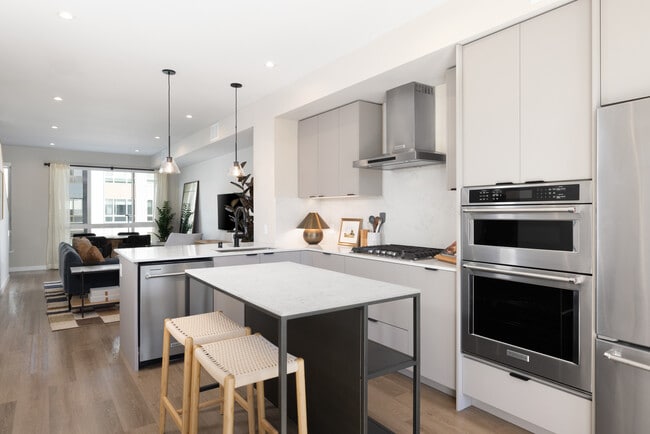 Signature Collection I 3-Bedroom Townhome Kitchen with light grey cabinetry, white marbled quartz countertops, and upgraded stainless steel appliances - Avalon Pleasanton