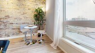 Located at 123 King St in downtown London, Ontario, this well-appointed single-floor unit offers a thoughtfully designed layout that blends industrial character with modern finishes. A defining architectural feature throughout the space is the stunning exposed brick wall, which lends warmth and texture to the living and dining areas. Large windows flood the space with natural light and provide views of the surrounding cityscape, complementing the light-toned hardwood flooring that runs through the main living areas. The combined kitchen and dining space is a functional highlight, featuring white shaker-style cabinetry, stone-look countertops, stainless steel appliances including a range and refrigerator, a stainless steel island with seating, and a sleek overhead range hood. Tile flooring anchors the kitchen zone, while the dining area transitions to hardwood, creating a natural distinction between the two spaces. The unit includes two bathrooms; one features a clean white vanity with a dark granite countertop, an oval undermount sink, chrome fixtures, and a framed mirror, while the second includes a full soaker tub with shower. The overall ambiance is modern yet welcoming, with the exposed brick providing a distinctive urban character that sets this space apart.