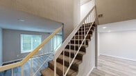 This two-story, 4-bedroom, 2-bathroom home in Macon, Georgia offers a well-organized layout spread across two floors. The main level hosts the combined kitchen and living area, two hallways, and convenient access to the carpeted staircase, which features a white baluster railing. The living room is bright and welcoming, with large windows and a sliding glass door fitted with vertical blinds that invite natural light and provide outdoor views. The kitchen is well-appointed with white shaker-style cabinetry, dark granite countertops, a teal subway tile backsplash, stainless steel refrigerator, and a black range. Light luxury vinyl plank flooring runs throughout both levels, lending a clean, cohesive look to the home. The upper floor houses the four bedrooms, each featuring recessed lighting, neutral toned walls, and windows overlooking the surrounding greenery. The spacious primary bedroom offers ample room for furnishings. Bedrooms include built-in closets for storage. The two bathrooms are finished with large-format marble-look tile surrounding a soaking tub. Textured ceilings and clean white trim complete the home's refreshed, move-in-ready aesthetic throughout.