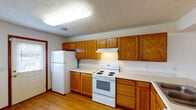 Located at 138 S Kendall Ave in Kalamazoo, Michigan, this two-floor residence offers a practical and well-organized layout across multiple living areas. The main living space features warm hardwood-style flooring and a bright window with vertical blinds, creating an open and airy atmosphere. A pass-through counter connects the living area to the kitchen, enhancing the sense of openness between the two spaces.

The kitchens are outfitted with warm oak cabinetry providing generous storage, white coil-burner electric ranges, white refrigerators, and light countertops. One kitchen features a side-entry door with an adjacent window, bringing in additional natural light. Both kitchen areas are functional and well-appointed for everyday use.

The bedrooms are carpeted in neutral tones and each includes a window with vertical blinds, offering natural light and a comfortable, quiet atmosphere. The bathrooms include warm wood-toned vanity cabinetry with white countertops. One bathroom features an extended vanity and a bathtub with a window above, while the second offers a combined shower and tub enclosure with a large mirror. Both bathrooms are finished with tile flooring and classic fixtures throughout.

Overall, the space presents a clean, functional design with consistent finishes across both floors, making it a practical choice in the Kalamazoo area.