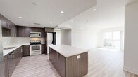 Located at 11110 Hartsook Street in North Hollywood, CA, this modern 3-bedroom, 3-bathroom residence offers a thoughtfully designed single-floor layout with clean, contemporary finishes throughout. Light wood-tone flooring flows seamlessly across the open-concept living and kitchen areas, creating a bright and cohesive atmosphere enhanced by recessed lighting.

The kitchen is a standout feature, showcasing rich dark wood cabinetry with sleek bar-pull hardware, white quartz countertops, a subway tile backsplash, and stainless steel appliances including a range, microwave, and refrigerator. A large central island provides ample prep and dining space, while a discreetly integrated stacked washer and dryer adds everyday convenience.

The living area is generously proportioned, featuring large sliding glass doors that open to a balcony and allow abundant natural light to fill the space. Each of the three bedrooms is bright and well-sized, with large windows framing neighborhood views and recessed lighting overhead.

The primary bedroom suite includes a spacious walk-in closet outfitted with built-in shelving and hanging rods, leading directly into a luxurious en-suite bathroom finished with marble-look tile flooring, a glass-enclosed shower and tub combination, and a dark wood vanity with a white countertop. The additional bathrooms mirror this refined aesthetic, maintaining a consistent, upscale design throughout the residence.
