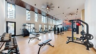 This state-of-the-art fitness center, located at 10 Tower St NW in Atlanta, GA, spans 1,740 square feet on a single floor. The facility boasts an impressive architectural design with soaring ceilings and expansive windows that flood the space with natural light, creating an energizing atmosphere for workouts. The interior features a sleek, modern aesthetic with clean white walls and warm wood accents.

The gym is equipped with a wide array of exercise equipment to cater to various fitness needs. The cardio section includes treadmills, ellipticals, and stationary bikes, all positioned to take advantage of the city views through floor-to-ceiling windows. A dedicated strength training area offers free weights, weight machines, and functional training equipment.

A standout feature is the vibrant mural depicting the Atlanta skyline at sunset, adding a touch of local flair and inspiration to workouts. The space is thoughtfully designed with separate zones for different types of exercises, ensuring a smooth flow and comfortable experience for users. High-quality flooring, strategically placed lighting, and excellent ventilation contribute to the overall premium feel of this fitness center.