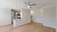 Located at 1235 Ashley Gardens Blvd in Charleston, SC, this well-appointed 2-bedroom, 2-bathroom single-story home offers a thoughtfully designed layout with modern finishes throughout. The open-concept kitchen and living area serves as the heart of the home, featuring light wood-look LVP flooring, crown molding, and a ceiling fan. The kitchen is outfitted with gray cabinetry, granite countertops, stainless steel appliances including a refrigerator, microwave, and range, and a peninsula with pendant lighting and an undermount sink — ideal for both cooking and casual dining. Large windows in the living area allow natural light to fill the space, with views of greenery outside. Both bedrooms are carpeted and include ceiling fans, with the secondary bedroom featuring a window overlooking lush outdoor scenery. The bathrooms mirror the kitchen's quality finishes, showcasing granite double vanities, gray cabinetry, and tub/shower combinations with tile surrounds. Two closets provide ample storage, including a spacious walk-in. A dedicated laundry room houses a full-size washer and dryer with overhead wire shelving. A light-toned hallway with LVP flooring connects all rooms cohesively, completing this clean and move-in-ready home.