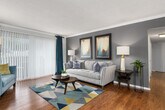 This well-appointed 2-bedroom, 2-bathroom residence is thoughtfully designed across a single floor, offering a functional and comfortable layout. The expansive living room is a standout feature, showcasing rich hardwood flooring, crown molding, and a large sliding glass door that invites abundant natural light. The space is framed by neutral gray accent walls, creating a modern yet welcoming ambiance.

Adjacent to the living room, the dining area provides a dedicated space for meals, accented by a overhead pendant light, crown molding, and the same warm hardwood flooring that flows throughout the common areas. The kitchen is efficiently laid out with tile flooring, dark granite countertops, white cabinetry, and a built-in desk nook, with a convenient pass-through connection to the dining room.

The primary bedroom is generously sized, featuring plush carpeting, large windows with natural light, and ample room for a full furniture arrangement. The second bedroom, also carpeted, includes a bright window and offers flexible use as a guest room or home office. Both bathrooms are finished with clean white vanities and neutral tile flooring. A hallway, closet, and built-in shelving near the living area round out this well-organized, comfortable residence.