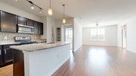 This single-floor residence is thoughtfully designed with an open-concept layout that seamlessly connects the kitchen, dining, and living areas. The kitchen is a standout feature, equipped with dark espresso cabinetry, stainless steel appliances, granite countertops, a mosaic tile backsplash, and a breakfast bar with pendant lighting overhead. Rich hardwood-style flooring flows throughout the main living spaces, adding warmth and continuity to the open floor plan. The spacious living room benefits from multiple windows that invite abundant natural light and is fitted with a ceiling fan for added comfort.

The primary bedroom is generously sized, featuring plush carpeting, a ceiling fan, and direct access to an en-suite bathroom. The primary bath is finished with tile flooring, dark cabinetry with granite countertops, and leads to a large walk-in closet with built-in shelving and hanging rods. Additional bedrooms are carpeted and well-lit by natural light through sizable windows. A pantry with open shelving provides practical storage near the kitchen. Throughout the residence, neutral tones, clean lines, and consistent finishes create a cohesive and modern aesthetic that is both functional and inviting.