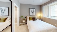 Located at 1910 S Union St in Anaheim, California, this single-floor residence offers a thoughtfully designed layout with modern finishes throughout. The kitchen is a standout feature, showcasing flat-panel cabinetry in a warm taupe wood-grain finish, crisp white quartz countertops, and a full suite of stainless steel appliances including a gas range, over-the-range microwave, dishwasher, and French door refrigerator. Open shelving adds a decorative touch while providing convenient storage. The bedroom is carpeted and generously sized, featuring a ceiling fan, large windows that invite natural light, and access to a spacious walk-in closet with built-in shelving and hanging space. The neutral gray wall tones create a calm and restful ambiance. The bathroom is finished with wood-look luxury vinyl plank flooring, a wide vanity with dual sinks, a large mirror with contemporary light fixtures, and a full soaking tub with shower combination. The living and dining areas, visible in the floorplan, extend the home's open and airy feel with hardwood-style flooring, connecting seamlessly to the bedroom and kitchen for a cohesive, functional flow throughout the residence.