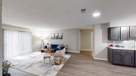 This single-floor residence offers a thoughtfully designed open-concept layout that seamlessly integrates the living, dining, and kitchen areas. The main living space is generously sized, featuring durable hardwood-style flooring, neutral-toned walls, and recessed lighting that creates a bright, welcoming atmosphere. A standout design element in the living area is a floor-to-ceiling tiled accent wall that frames the entertainment area, adding a bold architectural detail to the space. Large sliding glass doors allow natural light to pour in and provide outdoor access. The kitchen is well-equipped with dark espresso cabinetry, light countertops, a subway tile backsplash, stainless steel appliances, and a window that brings in additional natural light. The space includes two carpeted bedrooms, each offering a calm, restful environment. One bedroom features a spacious sliding-door closet, while the other benefits from a window with outdoor views. The full bathroom is clean and functional, outfitted with a tub-shower combination, wood-look flooring, and brushed nickel fixtures. A staircase visible in the layout suggests access to an additional level below.