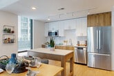 Located at 1771 N Pierce St in Arlington, VA, this well-designed 3-bedroom, 2-bathroom residence offers a thoughtfully planned single-level layout with modern finishes throughout. Light hardwood flooring flows seamlessly across all living areas, complemented by crisp white walls and recessed lighting that create a bright, airy atmosphere.

The open-concept kitchen is a standout feature, showcasing two-tone cabinetry with white upper cabinets and warm wood lower cabinets, a classic white subway tile backsplash, quartz countertops, and a full suite of stainless steel appliances including a Bosch range, built-in microwave, dishwasher, and refrigerator. Floor-to-ceiling windows flood both the kitchen and adjacent dining area with abundant natural light and views of the surrounding Arlington cityscape.

The spacious primary bedroom benefits from expansive windows with urban views, providing a serene retreat. The secondary bedrooms are similarly well-lit, each with large windows. Both bathrooms are elegantly finished with large-format tile flooring, wood-toned floating vanities, and illuminated mirrors. The primary bath features a glass-enclosed walk-in shower with dark tile surround, while the second bath offers a full soaking tub and shower combination. A dedicated laundry area, four closets, and a connecting hallway round out this efficient and stylish Arlington residence.