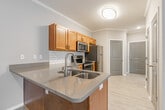 Located at Grand Island in Memphis, TN, this single-floor residence offers a thoughtfully designed layout that balances comfort and functionality. The kitchen is a standout feature, equipped with warm honey-toned cabinetry, a classic white subway tile backsplash, light quartz countertops, a stainless steel undermount sink, and a full suite of stainless steel appliances including a range, dishwasher, microwave, and refrigerator. Crown molding adds a refined touch throughout. The open living area is finished with light-toned luxury vinyl plank flooring and neutral gray walls, creating a bright and versatile space with direct access to a private exterior door. The bedroom is generously sized, featuring plush carpet flooring, a ceiling fan with light fixture, and a window fitted with white blinds that invites natural light. A spacious walk-in closet with multi-tier wire shelving provides ample storage. The bathroom includes a soaking tub and connects conveniently via a hallway to the bedroom. A dedicated in-unit laundry room accommodates a full-size washer and dryer with overhead wire shelving. Additional storage is available via built-in shelving near the entryway, rounding out this practical and comfortable Memphis residence.