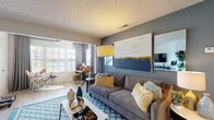 Located at Feather Sound Circle East in Clearwater, Florida, this single-floor residence offers a thoughtfully designed layout that balances comfort and contemporary style throughout. The open living area serves as the heart of the home, featuring light wood-look flooring, a textured ceiling, and a bold charcoal accent wall adorned with large-scale artwork. Natural light pours in through plantation-shuttered windows dressed with floor-length drapes, creating a bright and inviting atmosphere. A dedicated media nook with wood-look flooring and a sleek navy console provides a defined entertainment space that flows seamlessly into the main living zone. The kitchen is outfitted with white cabinetry, dark granite-style countertops, stainless steel appliances, and a peninsula with a breakfast bar — ideal for casual dining and meal preparation. Wood-look flooring continues throughout the main areas, connecting the spaces cohesively. The bedrooms offer plush carpeting, ceiling fans, and generous natural light from plantation-shuttered windows, each exuding a calm and restful ambiance. The bathroom features wood-look flooring, white cabinetry with brushed gold hardware, dark countertops, and a full soaking tub with tiled surround, combining clean lines with functional elegance throughout.