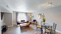 Located at 2616 Mission Rd in Tallahassee, FL, this single-floor unit offers a well-organized layout designed for comfortable everyday living. Wood-style flooring runs throughout, providing a cohesive and easy-to-maintain foundation across all rooms.

The entryway hallway leads into an open-concept living and dining area filled with natural light from a large sliding glass door dressed with vertical blinds and patterned curtains. The living room provides ample space for seating and entertainment, with a wall-mounted TV setup and a ceiling fan for added comfort.

Adjacent to the living area, the dining space connects directly to the kitchen through a pass-through opening. The galley-style kitchen is equipped with dark cabinetry, granite-look countertops, a double-basin sink, stainless steel appliances including a refrigerator and dishwasher, and track lighting overhead.

The unit includes two bedrooms, each featuring ceiling fans with light fixtures, textured walls, and wood-style flooring. Both rooms offer generous space for full-sized furnishings. The full bathroom includes a combined tub and shower, a dark-vanity with granite-look countertop, and a single-basin sink. Textured walls and ceilings are found throughout, giving the unit a consistent architectural character.