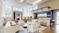 Located at 120 Bowery St in Virginia Beach, Virginia, this single-floor community clubhouse is a well-appointed gathering space defined by soaring ceilings, polished concrete floors, and an abundance of natural light streaming through oversized windows and transom glass panels throughout.

The main lounge area serves as the heart of the space, featuring a coffered ceiling with warm accent lighting, a stone-surround fireplace with a wall-mounted television, and generous seating arrangements with crisp white upholstered sofas and chairs arranged around low coffee tables — creating an open, sophisticated atmosphere ideal for socializing or relaxing.

Adjacent to the lounge, a full kitchenette offers warm wood cabinetry, stone countertops, a mosaic tile backsplash, stainless steel appliances, and a wall-mounted TV — designed to support events and everyday resident use. Pendant lighting adds a refined touch to the space.

A welcoming entry corridor features polished floors, decorative pendant lighting, and views that open directly into the lounge and game areas, establishing an immediate sense of arrival. The game room includes a pool table, mid-century style seating, and bold cityscape artwork beneath soaring ceilings, with large windows framing views of the surrounding landscape.

Throughout, the design balances modern elegance with approachable comfort, making this a versatile and visually striking community amenity space.