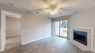This efficiently designed one-bedroom, one-bathroom residence offers a well-organized single-floor layout that maximizes every square foot. The living room serves as the centerpiece of the home, showcasing wood-look plank flooring, a textured ceiling with a ceiling fan, and a tile-surround fireplace that adds warmth and character. A full-width sliding glass door floods the space with natural light and opens to a private balcony, offering pleasant outdoor views. The kitchen is thoughtfully appointed with white shaker-style cabinetry, light quartz countertops, a subway tile backsplash, a stainless steel sink, and black appliances including a range, dishwasher, and refrigerator. A closet pantry provides additional storage. The bedroom is carpeted for comfort, features a ceiling fan, a window with natural light, and benefits from generous closet space, including a full double-door closet. The bathroom is clean and functional, outfitted with white cabinetry, quartz countertops, brushed nickel hardware, and wood-look tile flooring. Neutral tones, updated finishes, and consistent flooring choices throughout create a cohesive and move-in-ready atmosphere.