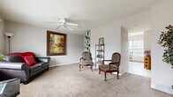 Located at 1114 SE Powell St in Topeka, Kansas, this two-story home offers a well-organized layout spread across two floors, accommodating two bedrooms, two bathrooms, a living room, dining room, office, and hallway. The entry foyer welcomes visitors with warm neutral tones, plush carpeting, and a bold dark front door flanked by a sidelight window. The living room is generously sized, featuring ceiling fans with light fixtures, soft carpet flooring, and windows that allow natural light to fill the space. The kitchen is equipped with warm oak cabinetry, a gas range, refrigerator, and ample counter space, flowing naturally into the bright dining area. The dining space benefits from a sliding glass door and windows overlooking a fenced outdoor area, creating an airy, connected feel. Both bedrooms are carpeted and include ceiling fans, natural light from windows, and closet storage — the primary bedroom offering a notably spacious footprint. The dedicated office provides a quiet, carpeted retreat with its own ceiling fan. The two bathrooms feature tile flooring and clean, functional finishes. Neutral wall tones and consistent carpeting throughout lend a cohesive, comfortable ambiance to the entire home.