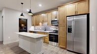 This 570 square foot apartment, located at BWR #208, offers a thoughtful layout maximizing space efficiency. The single-floor plan comprises one bedroom, one bathroom, a kitchen, a closet, and an additional room.

The kitchen stands out as a focal point, boasting light wood cabinetry that extends to the ceiling, providing ample storage. Stainless steel appliances, including a refrigerator, dishwasher, and over-the-range microwave, add a modern touch. A granite-topped island with an overhang serves as both a prep area and casual dining space. Pendant lights above the island enhance the ambient lighting.

The bathroom features a clean, white design with a spacious shower stall and a vanity with a marble-like countertop. Wood-look flooring extends throughout the apartment, creating a cohesive look and easy-to-maintain surface. The bedroom, while compact at 90 square feet, includes neutral-toned carpeting for comfort.

Overall, the apartment maintains a neutral color palette with white walls, contributing to a bright and airy feel. The layout appears to make efficient use of the available square footage, creating a comfortable living space in a compact footprint.
