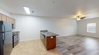 Located at 1705 Poplar St in Remerton, Georgia, this single-story residence offers a practical, open-concept floor plan designed for comfortable everyday living. The main living area features light wood-style laminate flooring and a ceiling fan, creating a bright and airy atmosphere. Natural light filters in through windows, enhancing the sense of openness throughout the space.

The kitchen is positioned centrally within the layout and features an island/peninsula with a granite-style countertop, an undermount sink, and warm wood cabinetry. Black appliances, including a refrigerator, electric range, and built-in microwave, provide a cohesive look. Tile flooring in the kitchen and adjoining areas offers a durable, easy-to-maintain surface.

The bedroom is generously proportioned, featuring light wood-style flooring, dual windows for ample natural light, a ceiling fan, and a closet. Two bathrooms serve the unit: one includes a vanity with a granite-style countertop and a tub/shower combination, while the second offers a compact vanity with matching finishes. A dedicated laundry area accommodates a full-size washer and dryer alongside a water heater, adding significant everyday convenience to this well-appointed residence.