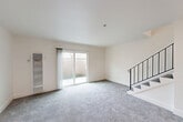 Located at 3329 Claremont Ct in Santa Rosa, CA, this two-story home offers a clean, functional layout spread evenly across two floors. The main level features a bright, open combined living and dining area finished with plush gray carpet and crisp white walls. A sliding glass door floods the space with natural light and provides direct access to the outdoor patio area. A staircase with a sleek black metal railing connects the two floors. Also on the main level, the kitchen is efficiently designed with white cabinetry featuring black hardware, light-toned countertops, a stainless steel sink and dishwasher, and an electric range — all complemented by light wood-style flooring and a window allowing in natural light. Upstairs, two carpeted bedrooms offer comfortable retreats, each with windows fitted with blinds for privacy. The primary bedroom is a well-proportioned space with ample room for furnishings. Three closets are distributed throughout the home, providing generous storage. Two full bathrooms include tub-shower combinations with white tile surrounds. Hallways on both levels facilitate smooth circulation throughout. The home's consistent neutral palette and clean finishes create a bright, move-in-ready atmosphere.