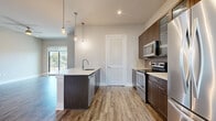 This contemporary two-floor residence offers a well-appointed layout designed with modern finishes throughout. The kitchen is a functional centerpiece, showcasing dark espresso cabinetry with sleek hardware, white quartz countertops, stainless steel appliances including a French-door refrigerator, electric range, and built-in microwave. A kitchen island with an undermount sink and pendant lighting adds both style and utility, while warm wood-look flooring flows through the open living and dining areas.

The living spaces are bright and airy, with large sliding glass doors opening onto private balconies that offer views of the surrounding cityscape and mature trees, flooding the interiors with natural light. Ceiling fans and roller shades enhance comfort throughout.

The bedrooms feature plush carpet flooring and generous proportions, with one bedroom benefiting from direct balcony access and sweeping urban views. The bathrooms are finished with neutral large-format tile, including a full bath with a soaking tub, glass-enclosed shower, and dark-framed vanity mirror, as well as a powder room featuring a floating vanity with a white countertop. The overall aesthetic is clean, modern, and cohesive across both floors.