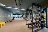 Located at 420 Mendocino Ave in Santa Rosa, California, this contemporary fitness and wellness facility offers a well-appointed, single-floor layout designed to support a complete health and recovery experience. Guests are welcomed by a stylish reception lounge featuring textured wall coverings, a living moss art installation, warm leather seating, and sculptural wood coffee tables — setting a refined, modern tone from the moment of arrival.

The expansive main gym floor is equipped with a comprehensive selection of strength and cardio equipment, including cable machines, free weights, benches, rowing machines, and treadmills. Exposed teal-painted ceilings with industrial ductwork and linear LED lighting give the space an energetic, urban aesthetic, while floor-to-ceiling windows draw in natural light and views of surrounding greenery. Mirrored walls extend the sense of depth throughout.

A dedicated studio room with light hardwood flooring, glass doors opening to an outdoor terrace, and a wall-mounted display provides an ideal setting for cycling and flexibility training. The hallway connecting functional zones features textured dark tile accent walls and warm wood cabinetry for an elevated transitional experience.

The two bathrooms offer spa-like finishes, including large-format tile, glass-enclosed showers with rain heads, brass fixtures, and built-in benches. A cedar-lined sauna rounds out the recovery amenities, delivering a serene, wellness-focused retreat within the facility.