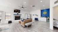 Located at 2600 W Ina Rd in Tucson, Arizona, this single-floor community space blends modern design with warm, functional interiors. The main lounge area serves as the heart of the space, showcasing light wood-look flooring, recessed lighting, and a ceiling fan overhead. A standout fireplace with a striking geometric tile surround and bold blue mantel anchors one wall, complemented by a wall-mounted flat-screen TV above. Comfortable seating and an open layout create an inviting atmosphere for gathering.

A vibrant blue accent wall bearing the "MC" monogram logo adds brand character, flanked by a white cabinetry station ideal for refreshments. Decorative floating shelves and curated artwork contribute to the space's polished yet approachable aesthetic.

A dedicated private office, branded with the "Sharing The Good Life Foundation" signage, features a large desk, guest seating, and ample natural light from multiple windows — well-suited for professional meetings or administrative use.

Multiple dining areas provide flexible seating options, including a formal dining table with upholstered chairs set on a blue-toned area rug, and a casual high-top table set against a deep blue accent wall. Natural light flows generously throughout via slatted blinds, enhancing the bright, open character of the entire space.