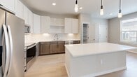 Located at 20130 Schiel Road in Cypress, Texas, this single-story home showcases a thoughtfully designed layout with modern finishes throughout. The open-concept kitchen is a standout feature, boasting white upper cabinetry paired with warm wood-toned lower cabinets, crisp white quartz countertops, a subway tile backsplash, stainless steel appliances, and a central island with pendant lighting overhead. A walk-in pantry and recessed lighting add to the kitchen's functionality and appeal. Light wood-look flooring flows through the main living areas, complementing the neutral, warm-toned walls. The living area benefits from natural light streaming through large windows and a glass-panel door, creating a bright and welcoming atmosphere. The bedrooms feature plush carpet flooring, ceiling fans, and windows that bring in natural light. Bedrooms include walk-in closets with built-in shelving for ample storage. The bathrooms are finished with wood-toned vanities, white quartz countertops, and large framed mirrors. The primary bathroom features a dual-sink vanity with stylish lighting, while secondary bathrooms include a tub-shower combination with tile surround. A dedicated laundry area with built-in shelving provides added convenience, completing this well-appointed home.