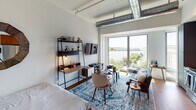 Located at 1900 Half St SW in Washington, DC, this modern studio unit offers an open-plan layout that seamlessly integrates the living, sleeping, and kitchen areas into one cohesive space. An exposed industrial-style ductwork system runs along the soaring ceilings, lending a loft-inspired character that sets the tone for the entire unit.

The kitchen is a standout feature, outfitted with warm wood cabinetry, rich dark granite countertops, a bold slate-blue subway tile backsplash, and a full suite of stainless steel appliances including a refrigerator, dishwasher, electric range, and over-the-range microwave. The living area is anchored by large floor-to-ceiling windows that frame sweeping waterfront views of the Anacostia River and the surrounding greenery, flooding the space with abundant natural light. Rich hardwood flooring runs throughout, adding warmth to the contemporary aesthetic.

The sleeping area is integrated naturally into the open floor plan, benefiting from the same generous light and river views. A private bathroom features large-format tile flooring, cool gray walls, dark granite vanity countertops, and a glass-enclosed shower with dark subway tile surround, delivering a clean and refined finish. This thoughtfully designed studio offers a compelling blend of urban industrial style and waterfront serenity in the heart of Southwest DC.
