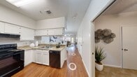 This single-story residence offers a thoughtfully designed layout encompassing one bedroom, three bathrooms, a dedicated office, and a combined dining, kitchen, and living area. Warm hardwood flooring flows throughout the main living spaces, complemented by neutral-toned walls and textured ceilings with ceiling fans in key rooms. The open-concept kitchen features white cabinetry, granite countertops, a stainless steel double sink, a black dishwasher, and a black electric range — all connecting seamlessly to the dining area and living room. The dining space accommodates an intimate setting and opens to the kitchen via a pass-through counter. The living room is bright and inviting, with a large window and glass door that allow abundant natural light and outdoor views. The primary bedroom offers a comfortable, carpeted retreat with dual windows and a ceiling fan. The primary bathroom includes a double vanity with granite countertops, a walk-in tiled shower, and hardwood flooring. The office is a carpeted, well-lit room with its own ceiling fan, suitable for focused work or a flexible-use space. Three bathrooms in total ensure convenience throughout the home. The overall ambiance is clean, modern, and functional.