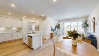 Located in San Diego, CA 92122, Unit 307 is a thoughtfully designed 2-bedroom, 3-bathroom residence that combines modern finishes with a bright, airy aesthetic throughout. Light wood flooring runs seamlessly across all rooms, complementing the clean white walls and creating a cohesive, contemporary feel.

The kitchen is a standout feature, boasting white shaker cabinetry extending to the ceiling, quartz countertops, stainless steel appliances, and a geometric tile backsplash with under-cabinet lighting. An island provides additional prep and storage space.

The living room is open and inviting, with recessed lighting and a sliding glass door that opens to a private balcony, offering pleasant outdoor views of the surrounding San Diego neighborhood.

The primary bedroom is generously sized, featuring its own sliding door to the balcony and a walk-in closet with multi-tier shelving. The additional bedroom includes a built-in closet and a bright window with neighborhood views.

All three bathrooms are finished with white vanity cabinetry, quartz countertops, and framed mirrors, maintaining a clean, consistent design language. A dedicated hallway connects the rooms efficiently, and the overall layout maximizes the comfortable square footage available in this well-appointed San Diego residence.