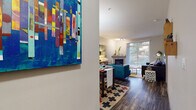This single-floor residence offers a well-organized layout that connects living, dining, kitchen, and sleeping areas with a cohesive modern aesthetic. Dark hardwood-style flooring runs throughout, providing a warm, grounding contrast to the light-toned walls and ceilings.

The living room is a standout space, anchored by a fireplace and bathed in natural light from a large sliding glass door that opens to a private balcony with outdoor views. The area comfortably accommodates a full seating arrangement and flows directly into the dining space, which sits adjacent to the kitchen.

The kitchen is well-appointed with dark espresso cabinetry, stainless steel appliances including a range, microwave, and refrigerator, light quartz-style countertops, and a subtle tile backsplash. A peninsula counter doubles as a casual bar or prep area, and the layout offers ample storage throughout.

Two bedrooms each feature windows with outdoor views, dark hardwood-style floors, and sufficient space for a queen or larger bed with nightstands. Each room has a calm, restful atmosphere.

The bathrooms include tub-shower combinations, dark cabinetry vanities with light countertops, large mirrors, and the same consistent flooring found throughout the unit.
