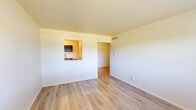 Located at 1400 Twombly Rd in DeKalb, Illinois, this 2-bedroom, 1-bathroom unit offers a practical and efficiently arranged single-floor layout. Light wood-style flooring runs consistently throughout the entire space, lending a clean and cohesive look to every room.

The living room serves as the main entry point and common area, featuring neutral white walls, a front entry door, and an open connection to the rest of the unit. The kitchen is compact yet functional, outfitted with dark cabinetry, a gas range, a full-size refrigerator, and a stainless steel sink with counter workspace, all set over matching light flooring.

Both bedrooms are well-proportioned with neutral walls and large windows that allow natural light and outdoor views of surrounding greenery. The spacious primary bedroom includes a louvered double closet for ample storage. The second bedroom also benefits from good natural light and a window with an exterior view. Each bedroom includes overhead ventilation.

The bathroom is finished with white wall tile surrounding a full tub/shower combo, a pedestal sink with a medicine cabinet mirror, and built-in open shelving for added storage convenience.

Overall, the unit presents a clean, move-in-ready aesthetic with consistent finishes and a straightforward layout suited for comfortable everyday living.