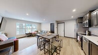 Located at 1625 Marshall Ave in St. Paul, Minnesota, this single-floor unit offers four bedrooms and two full bathrooms within a well-designed, efficiently laid-out floor plan. The open-concept kitchen and living area serves as the heart of the home, where light wood flooring flows seamlessly throughout. The kitchen is outfitted with stainless steel appliances — including a full-size refrigerator, range, microwave, and dishwasher — complemented by dark wood cabinetry and a classic white subway tile backsplash with light countertops. A dining area with a bar-height table sits just adjacent, creating a natural transition between cooking and gathering spaces. The living room benefits from a large picture window that invites natural light and provides views of the surrounding neighborhood streetscape. Each of the four bedrooms is comfortably sized, featuring windows with blinds, light flooring, and neutral wall tones that create a calm, functional environment. The primary bedroom offers a notably spacious feel. Both bathrooms follow a consistent design with dark wood vanities, white countertops, large mirrors, and shower-tub combinations. A hallway connects the private spaces, completing this practical and cohesive floor plan.