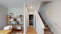 Located at 1211 First Edition Dr in Durham, NC, this three-story home offers a well-organized layout across its multiple levels, beginning with an attached garage on the ground floor. The garage provides ample vehicle storage, includes an automatic opener, and houses the electrical panel, offering practical utility from the start.

The main living level showcases an open-concept design where the kitchen flows seamlessly into the living area. The kitchen features dark cabinetry, stainless steel appliances, a subway tile backsplash, and an extended white quartz peninsula with an undermount sink and pendant lighting above. Hardwood-style flooring runs throughout, enhancing the bright, airy feel. A convenient half bath on this level includes hardwood-style flooring and a window with blinds.

A dedicated office space provides a quiet work area, finished with the same hardwood-style flooring and neutral walls. The stairwell connecting the floors features carpet treads and a clean white railing system.

Upper-level bedrooms are carpeted and well-lit by multiple windows dressed with blinds and sheer curtains, creating a calm, restful atmosphere. A full bathroom includes dark vanity cabinetry with a white countertop and a glass-enclosed walk-in shower, completing this thoughtfully designed home.
