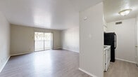 Located at 13450 Esperanza Rd in Dallas, TX, this one-bedroom, one-bathroom unit is thoughtfully laid out across a single floor. The open-concept living, dining, and kitchen area serves as the heart of the home, featuring light-toned hardwood-style flooring that extends throughout most of the space and crisp white walls that create a clean, bright atmosphere. A sliding glass door in the living area opens to a private balcony, allowing natural light to pour in and offering outdoor views of surrounding trees. The galley-style kitchen is efficiently organized with white cabinetry, a white electric range, a black refrigerator, a stainless steel sink, and a pass-through window that connects to the main living area. A pantry provides additional storage. The bedroom features darker hardwood-style flooring, a large window that brings in natural light, and direct access to multiple closets. The full bathroom is finished in white, featuring a tub-shower combination with tiled surround, a toilet, and a vanity with sink. A hallway connects the main living spaces to the bedroom and bathroom, completing the functional and straightforward floor plan. Three closets throughout the unit offer generous storage for everyday needs.