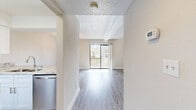 Located at 349 Scottsdale Square in Winter Park, Florida, this two-bedroom, two-bathroom home is thoughtfully laid out across two floors. The main level encompasses the primary living areas, including an open-concept living room, dining room, and kitchen. The kitchen is a standout feature, outfitted with crisp white shaker cabinetry, granite countertops, a peninsula with a breakfast bar, and a full suite of stainless steel appliances including a French door refrigerator, electric range with over-the-range microwave, and dishwasher. Light wood-style flooring runs throughout the main level, lending a clean, cohesive aesthetic. The living room is bright and airy, benefiting from a sliding glass door that opens to a private outdoor balcony. Upstairs, both bedrooms are carpeted for comfort. The primary bedroom features soaring vaulted ceilings with a clerestory window that draws in natural light, creating an open, elevated feel. The second bedroom includes a ceiling fan and a double-door closet. The two bathrooms are well-appointed — one with a glass-enclosed walk-in shower and the other with a soaking tub and stylishly tiled surround featuring decorative mosaic accents. Granite vanity tops and wood-look flooring complete the bathrooms' refined look.