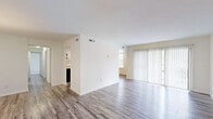 Located at 1113 Craftsman Dr in Virginia Beach, Virginia, this single-floor residence offers a clean, updated interior designed for comfortable everyday living. The open living and dining area is finished with durable wood-look flooring in a cool grey tone, crisp white walls, and a large sliding glass door fitted with vertical blinds that floods the space with natural light and provides direct outdoor access. A secondary window further enhances the brightness of the open layout.

The kitchen is well-appointed with white shaker-style cabinetry, granite-look countertops, and black stainless steel appliances including a gas range and a full-sized refrigerator. A tray ceiling with a central light fixture adds architectural interest overhead, while the wood-look flooring continues seamlessly throughout.

The bedrooms are carpeted in a warm neutral tone, offering a comfortable retreat. The primary bedroom features dual closets with bi-fold doors, providing generous storage capacity, and connects to a private bathroom with white vanity cabinetry and a well-lit mirror. Additional bedrooms include natural window light and individual closet space.

Throughout the residence, a consistent neutral color palette, updated finishes, and thoughtful layout contribute to a bright, functional, and move-in-ready living environment.