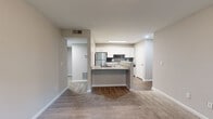 This thoughtfully designed 1-bedroom, 1-bathroom residence offers a functional and modern single-floor layout. The open-concept kitchen and living area serves as the heart of the home, featuring a peninsula with granite countertops and a built-in cooktop, crisp white cabinetry, dark subway tile backsplash, and stainless steel appliances including a refrigerator and dishwasher. Wood-look flooring runs throughout the kitchen and entry areas, transitioning to plush carpet in the living and bedroom spaces, creating a warm and comfortable feel. The living area provides generous room for furnishings and flows seamlessly from the kitchen peninsula. The bedroom is a well-proportioned retreat, carpeted for comfort, with a window offering views of lush greenery and access to a dedicated closet. Neutral, warm-toned walls throughout lend a clean and cohesive aesthetic. The bathroom is fitted with a full tub-shower combination, chrome fixtures, and wood-look flooring. A hallway connects the main living spaces to the bedroom and bathroom, providing a practical and organized flow. The unit also includes an additional unclassified room, offering flexible use potential.