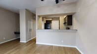 This single-floor residence is designed with an open, efficient layout that connects the main living areas seamlessly. The living room is a bright, open space highlighted by warm wood-look flooring, neutral taupe walls, and a large window fitted with blinds that invites natural light while maintaining privacy. A ceiling fan with integrated lighting provides both comfort and illumination. The kitchen is accessible via a pass-through counter with a granite-look surface, offering a convenient bar-style connection to the living area. Inside, the kitchen is equipped with dark espresso cabinetry, matching black appliances including a refrigerator, electric range, and built-in microwave, along with a double-basin sink set into a countertop that mirrors the pass-through surface. Wood-look flooring continues throughout the kitchen. A dedicated dining area sits adjacent to the kitchen, also featuring the same flooring and a ceiling fan overhead, with a closet providing additional storage. The bathroom is well-appointed with dark cabinetry above the toilet for extra storage, a granite-look vanity countertop with an undermount sink, a mirror, and a shower-tub combination. Consistent use of dark cabinet finishes and neutral wall tones throughout the space creates a cohesive and modern aesthetic.