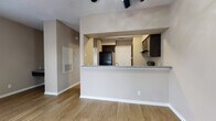 This single-floor residence is designed with an open, efficient layout that connects the main living areas seamlessly. The living room is a bright, open space highlighted by warm wood-look flooring, neutral taupe walls, and a large window fitted with blinds that invites natural light while maintaining privacy. A ceiling fan with integrated lighting provides both comfort and illumination. The kitchen is accessible via a pass-through counter with a granite-look surface, offering a convenient bar-style connection to the living area. Inside, the kitchen is equipped with dark espresso cabinetry, matching black appliances including a refrigerator, electric range, and built-in microwave, along with a double-basin sink set into a countertop that mirrors the pass-through surface. Wood-look flooring continues throughout the kitchen. A dedicated dining area sits adjacent to the kitchen, also featuring the same flooring and a ceiling fan overhead, with a closet providing additional storage. The bathroom is well-appointed with dark cabinetry above the toilet for extra storage, a granite-look vanity countertop with an undermount sink, a mirror, and a shower-tub combination. Consistent use of dark cabinet finishes and neutral wall tones throughout the space creates a cohesive and modern aesthetic.