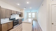 This 1-bedroom, 1-bathroom residence in Smyrna, Georgia offers a thoughtfully laid-out floor plan that maximizes every inch of its comfortable footprint. The open-concept design seamlessly connects the kitchen and living area, creating a bright and airy atmosphere enhanced by recessed lighting and a ceiling fan overhead.

The kitchen is a standout feature, equipped with rich dark-toned cabinetry, granite countertops, and a full suite of stainless steel appliances including a gas range, dishwasher, and refrigerator. A central kitchen island with a granite surface provides additional prep space and serves as a natural dividing point between the kitchen and living area. Light hardwood-style flooring runs throughout the unit, contributing to a clean, modern aesthetic.

The living area benefits from large windows dressed with horizontal blinds, allowing ample natural light to fill the space. The bedroom is a comfortable, well-proportioned room featuring its own ceiling fan, two windows, and the same warm hardwood-style flooring. Two closets provide generous storage throughout the unit. A utility room and a full bathroom round out the layout, with the bathroom conveniently accessible from the main hallway. The overall ambiance is clean, contemporary, and move-in ready.