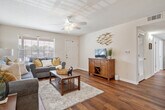 This single-story residence offers a thoughtfully organized floor plan comprising a living room, dining room, two bedrooms, one full bathroom, a hallway, and a closet. The living room serves as the central gathering space, featuring rich hardwood flooring, a ceiling fan, and a window that allows natural light to fill the room. The layout flows directly into the dedicated dining area, which is distinguished by an elegant chandelier and hardwood flooring, creating a formal yet welcoming atmosphere for meals.

The two bedrooms are carpeted for comfort, each equipped with a ceiling fan and windows that provide natural light. The primary bedroom offers a closet and ample space for furnishings. The second bedroom is similarly sized and well-lit.

The full bathroom includes wood-style flooring, a vanity with granite-style countertops, white cabinetry, and a toilet. Neutral wall tones are consistent throughout the residence, contributing to a cohesive and calm aesthetic. Textured ceilings are present in all rooms. The overall layout is efficient and functional, making practical use of the available space across the single floor.